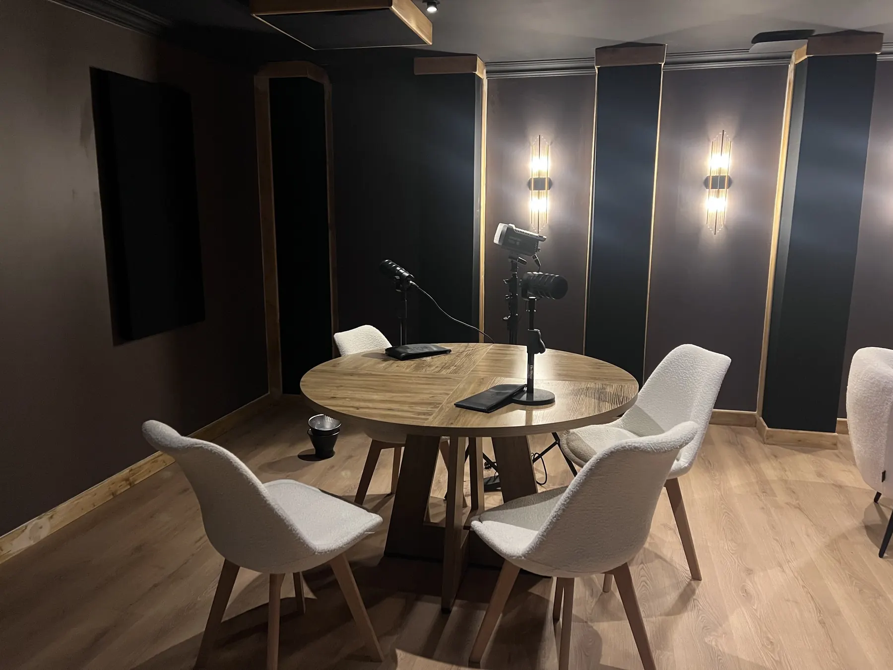 Détail de la salle de podcast : panneaux en cadres bois avec liseré doré et éclairage.